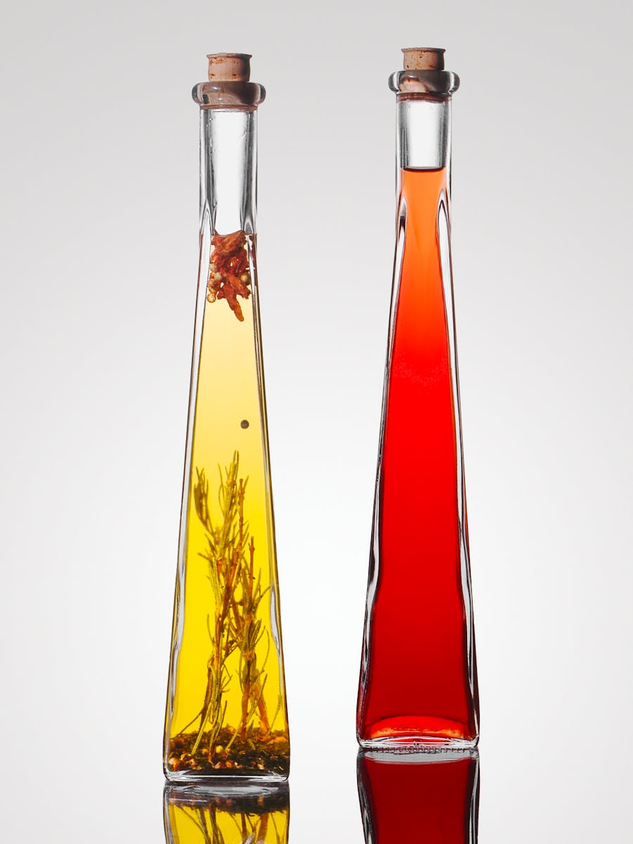 Stylish tall bottles of olive oil with herbs and red vinegar, perfect for gourmet cuisine.