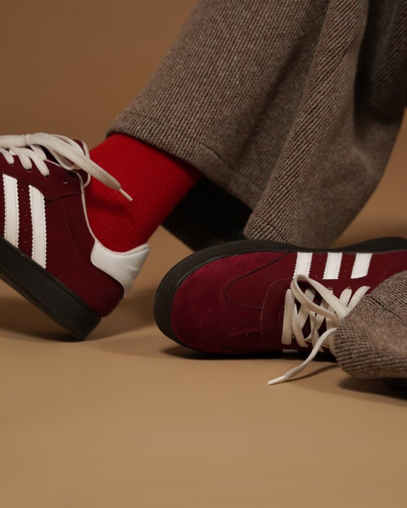 Close-up of burgundy sneakers paired with red socks, showcasing modern fashion trends.