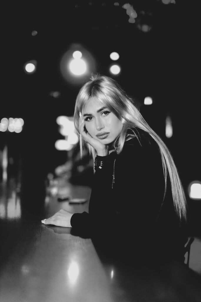 Captivating black and white portrait of a woman in a bar setting at night.