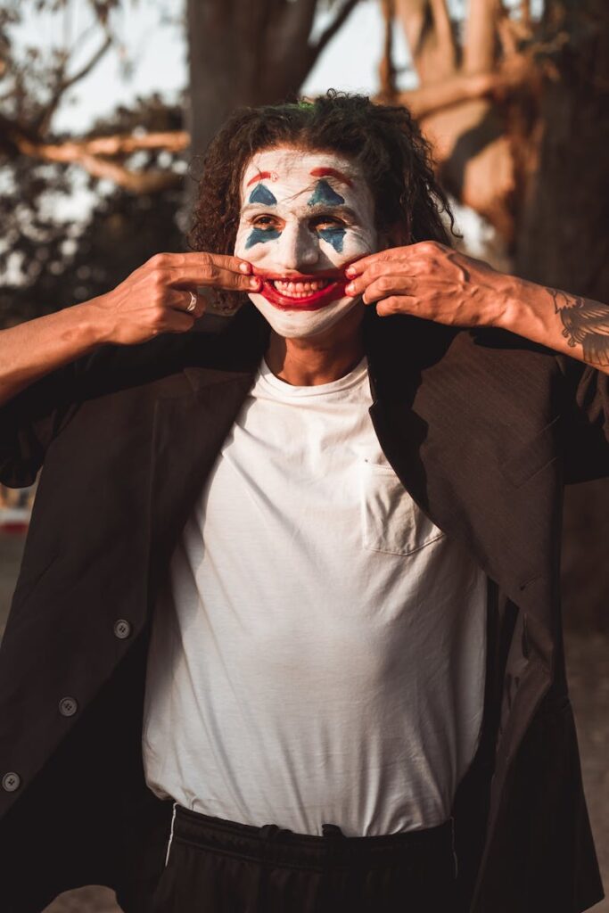 Close-up portrait of a man wearing Joker makeup outdoors, showcasing a creepy smile.