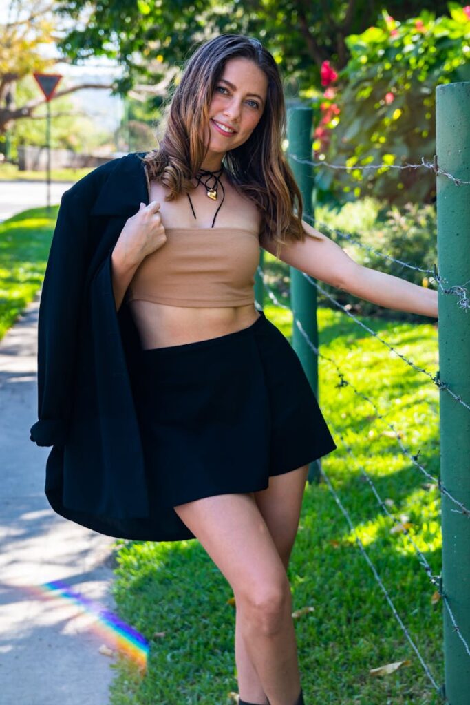 Young woman in a mini skirt and blazer poses outdoors against a vibrant El Salvador backdrop.