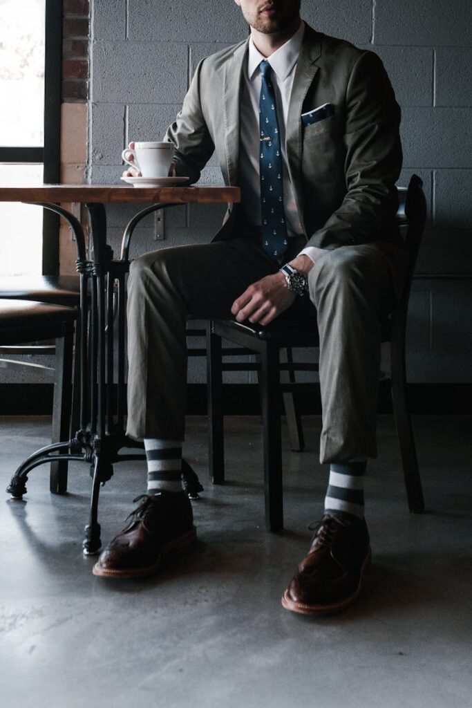 A man in a designer suit enjoys coffee in a chic cafe setting.