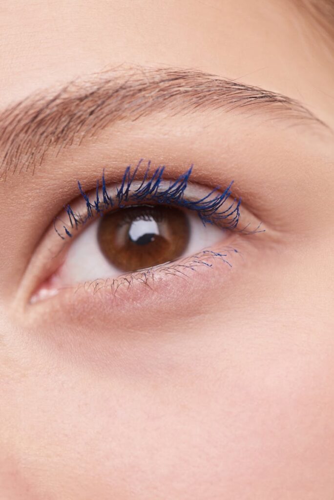 Close-up of a brown-eyed woman wearing blue mascara showcasing natural beauty.