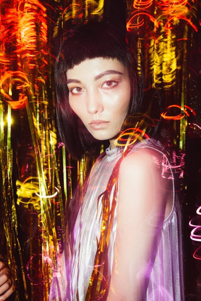 Colorful portrait of an Asian female model with creative lighting and party decorations.