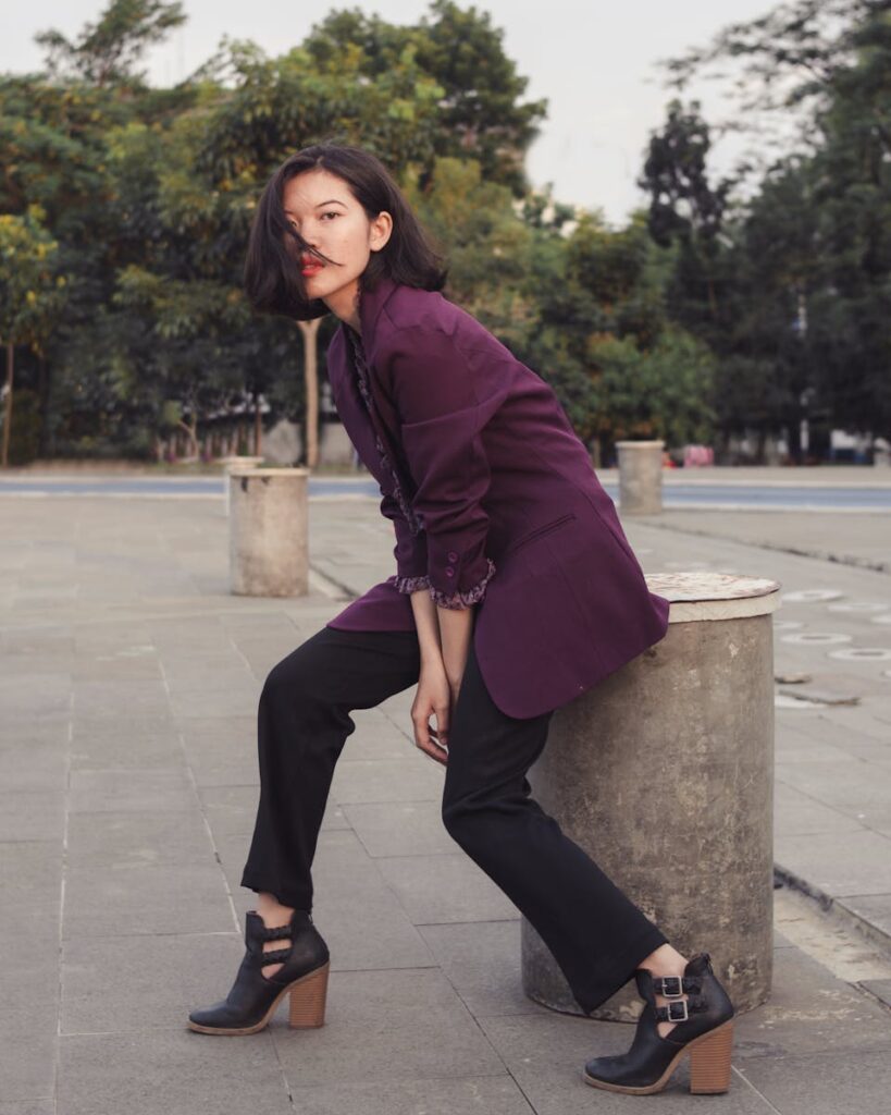Young woman in a fashionable urban setting wearing a purple blazer and black pants.
