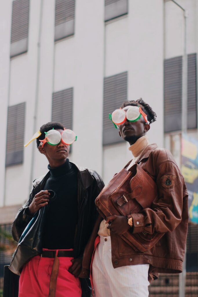 Two fashionable men wearing quirky eyewear, posing stylishly in an urban setting.