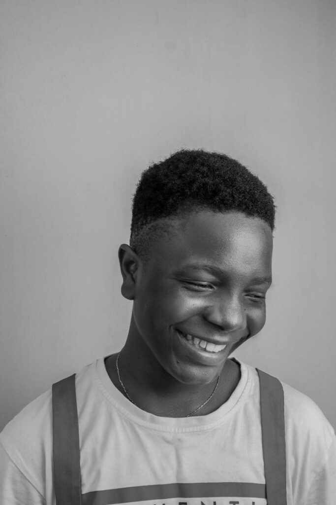 A monochrome portrait of a smiling teenage boy exuding happiness.