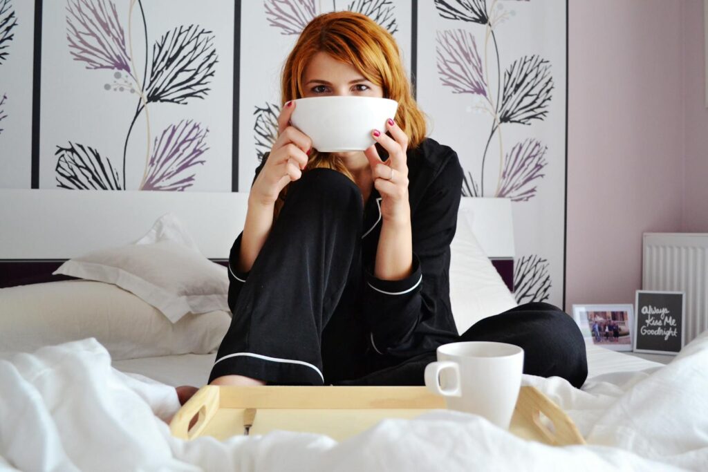 A woman enjoys a cup of coffee in a stylish and cozy bedroom, perfect for relaxation.
