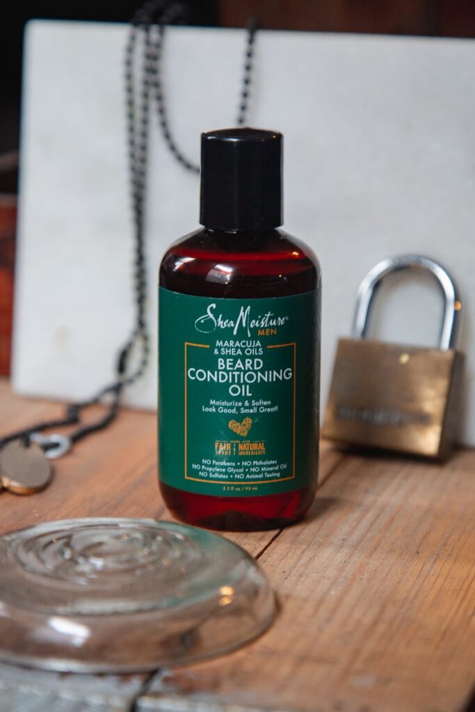 Beard conditioning oil bottle displayed on rustic wooden background.