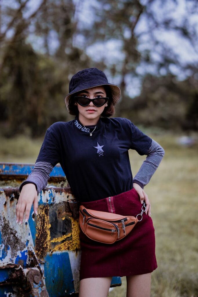 Fashion-forward young woman outdoors with sunglasses and bucket hat, showcasing casual style.