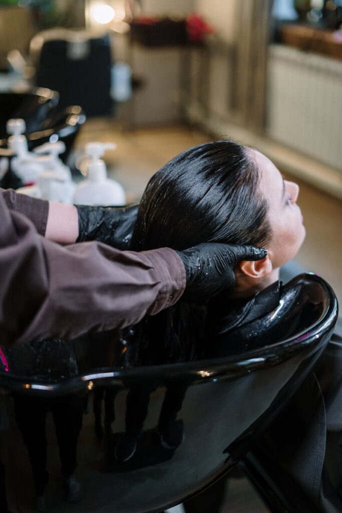 A professional hairstylist washing a woman's hair in a modern salon setting, ensuring quality haircare.