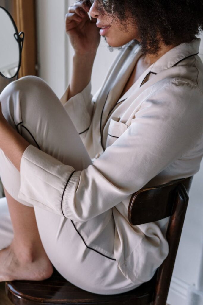 A woman in soft pajamas seated by a window, embracing a calm morning routine.