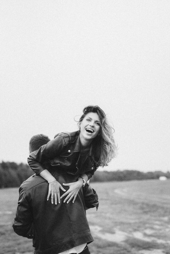 A joyful couple in leather jackets enjoying a playful moment outdoors.