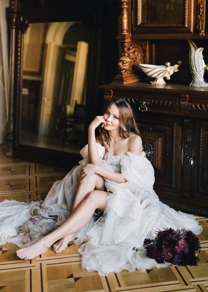 Elegant woman in wedding gown sitting in vintage room with bouquet.