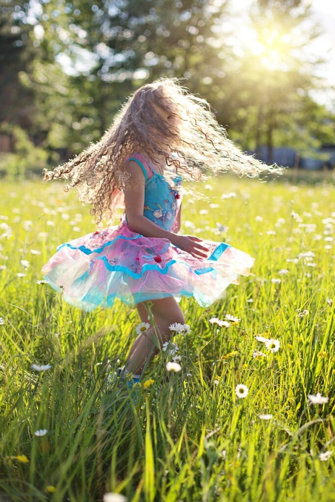 A carefree young girl dancing in a sunlit meadow filled with daisies.