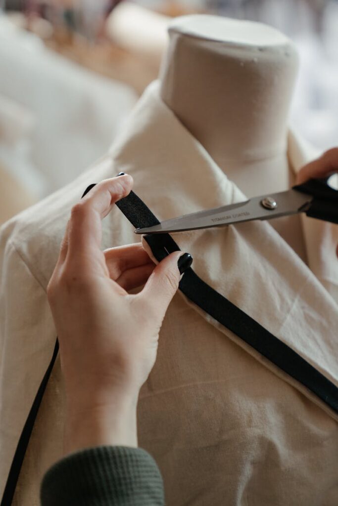 A seamstress cuts fabric around a mannequin in a fashion workshop, showcasing the art of tailoring.
