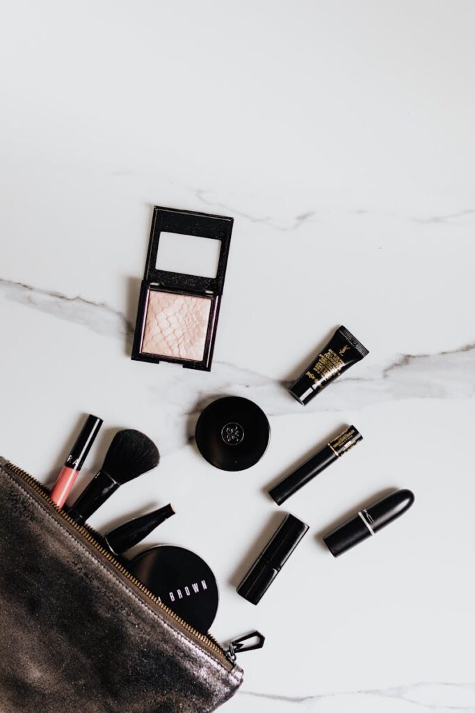 Top view of makeup essentials arranged on a marble surface, highlighting beauty products and tools.