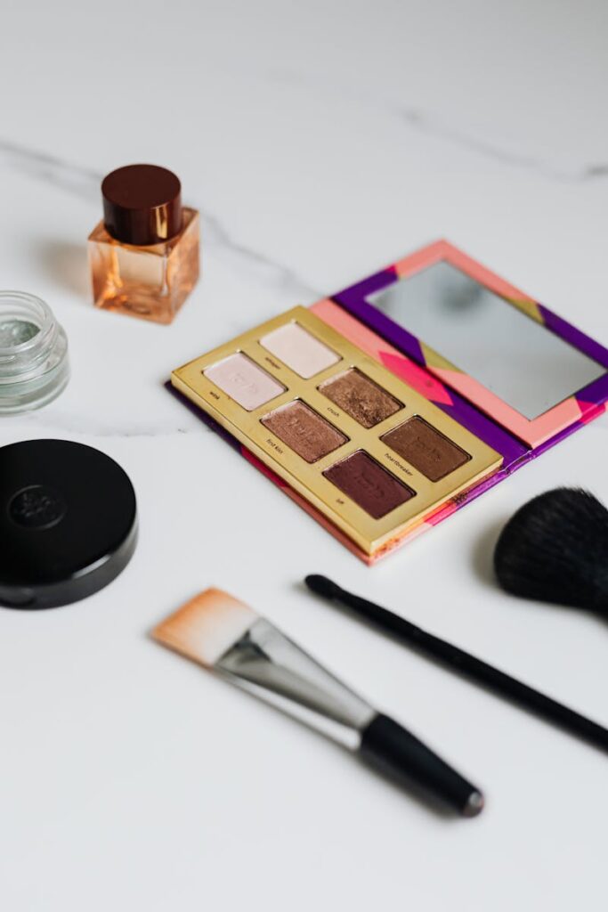 A stylish flat lay of cosmetics featuring an eyeshadow palette and brushes.