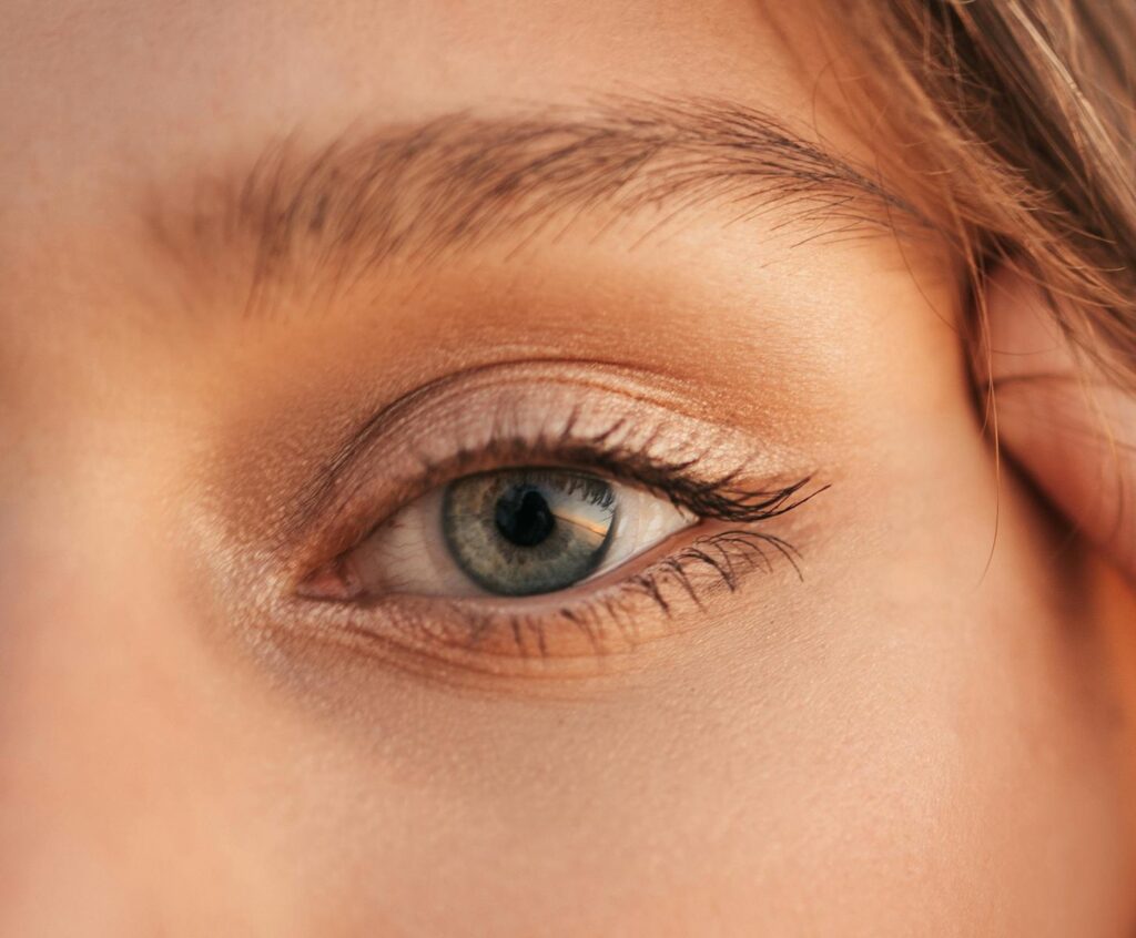 Detailed close-up of a human eye with visible eyelashes, skin texture, and natural lighting.