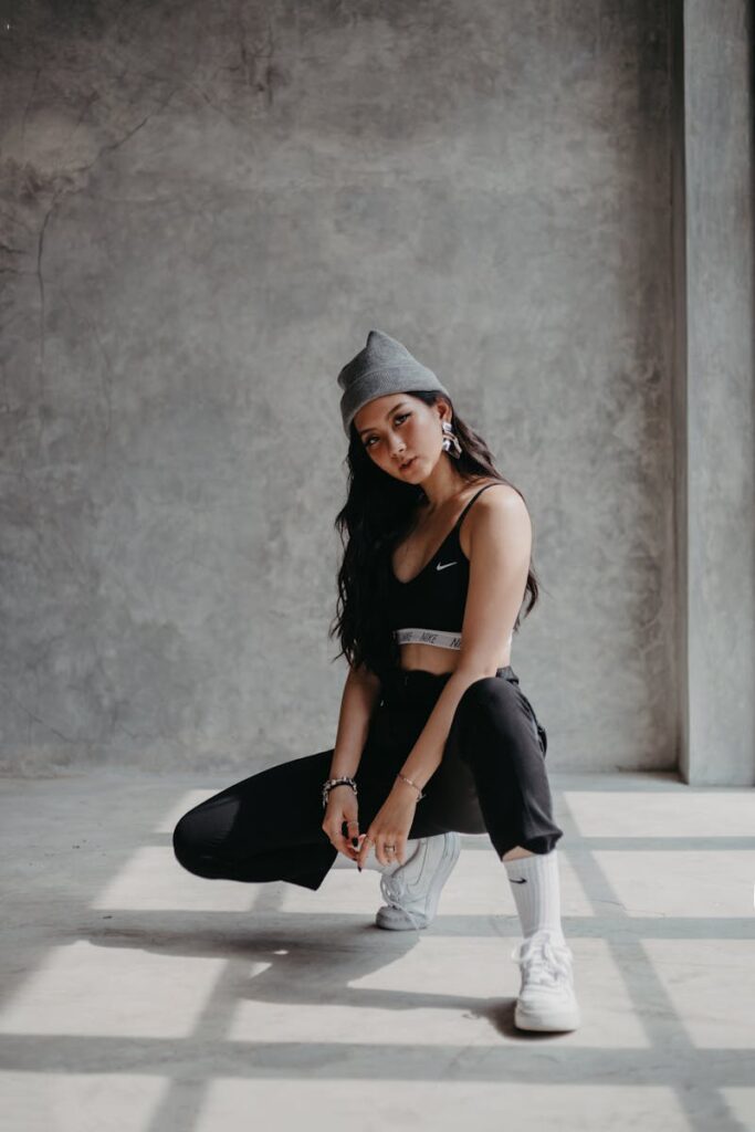 Stylish woman in sports bra and beanie posing indoors with a modern vibe.