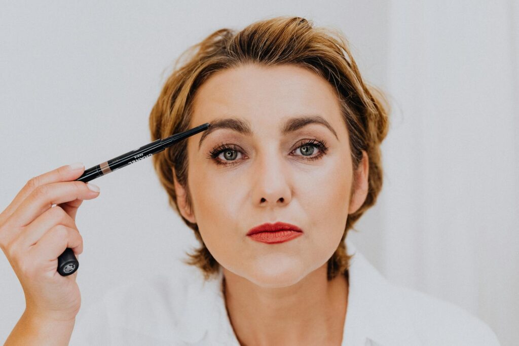 A close-up portrait of a woman applying eyebrow pencil, showcasing beauty and elegance.