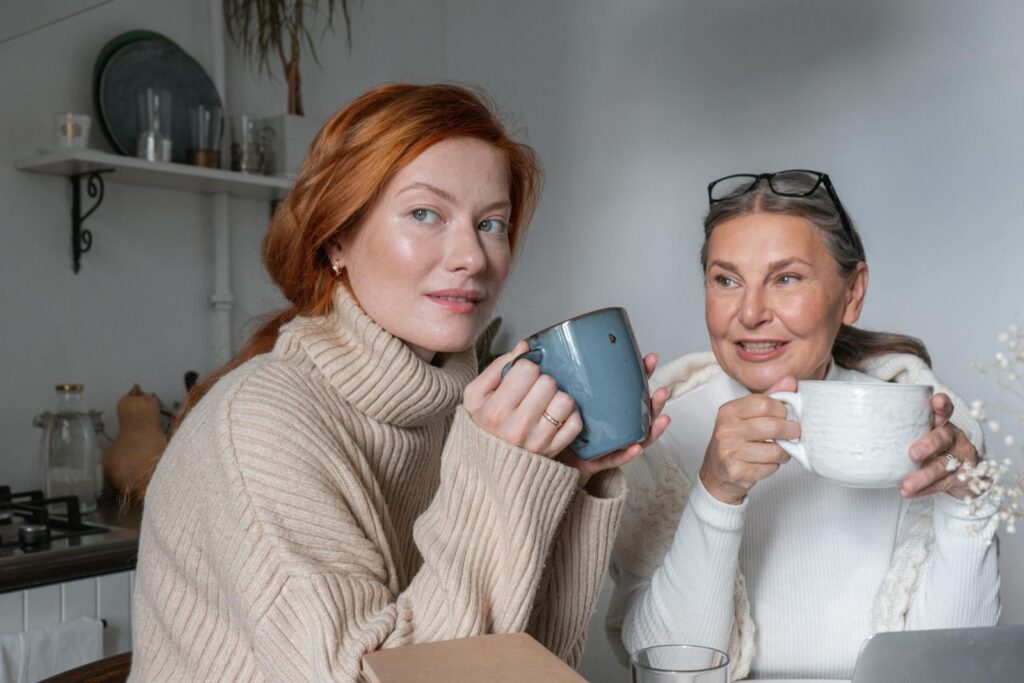 A mother and daughter share a warm moment, enjoying coffee indoors.