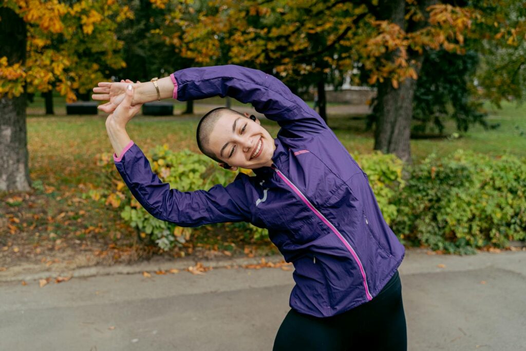 Woman enjoying outdoor stretching exercise in vibrant autumn park.