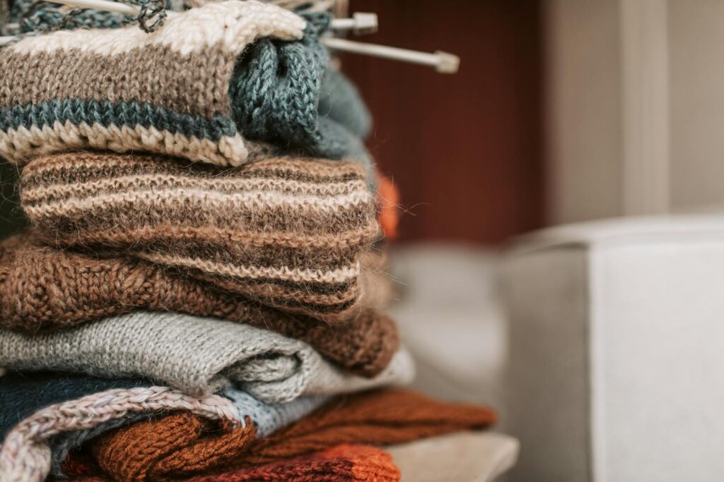 A stack of handmade knitted sweaters with knitting needles, exuding warmth and craftsmanship.