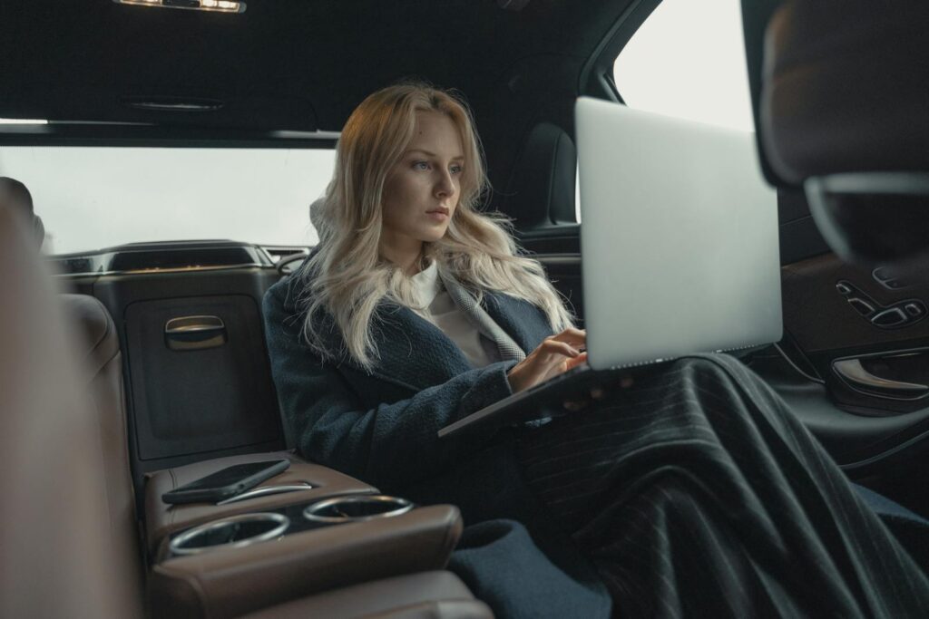Businesswoman working on her laptop in the back seat of a luxury car.