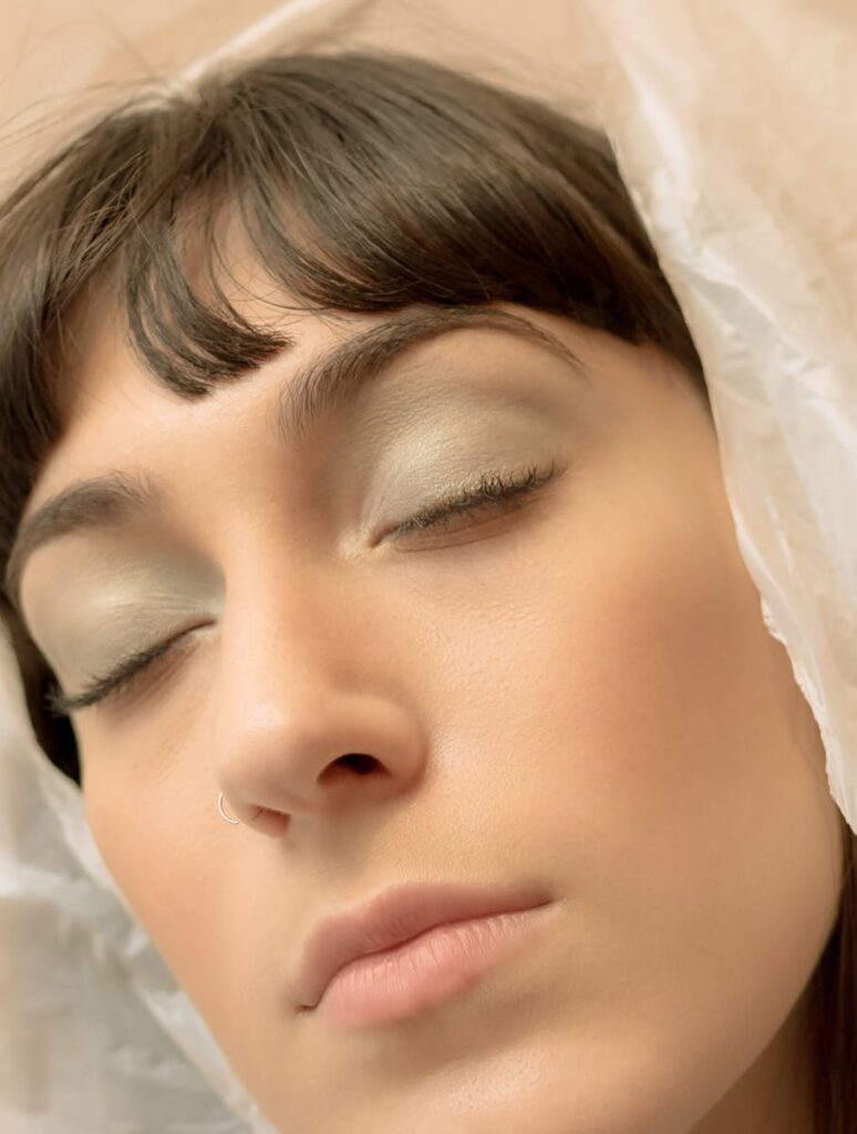 A close-up portrait of a woman with eyes closed, showcasing serene beauty and elegance.