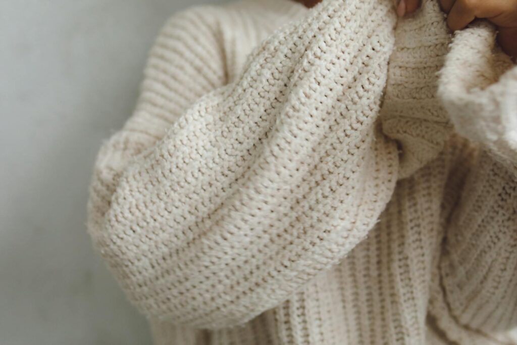 Soft beige knitted sweater captured in a cozy close-up view.
