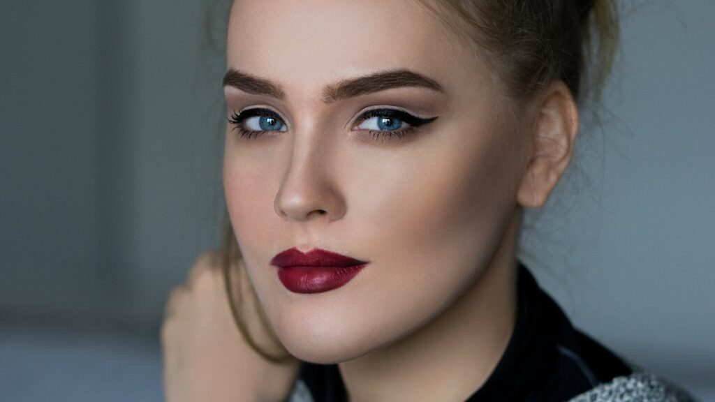 Close-up portrait of an elegant woman with striking makeup and blue eyes.