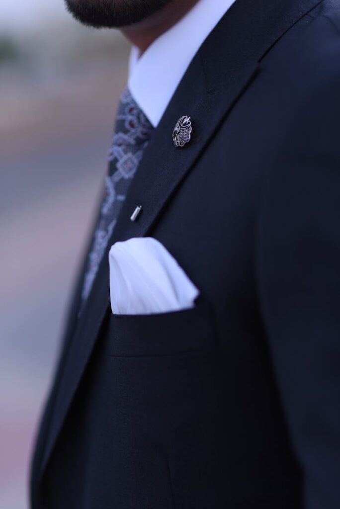 Close-up of a man in a stylish suit with a pin and pocket square.