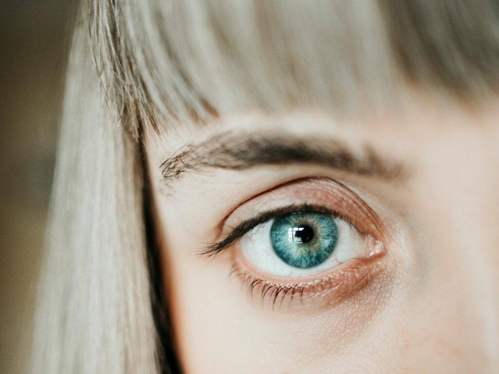 A macro shot of a blue human eye highlighting the detailed iris and eyelashes.