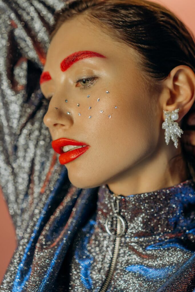 Artistic portrait of a stylish woman with bold makeup and glitter details.