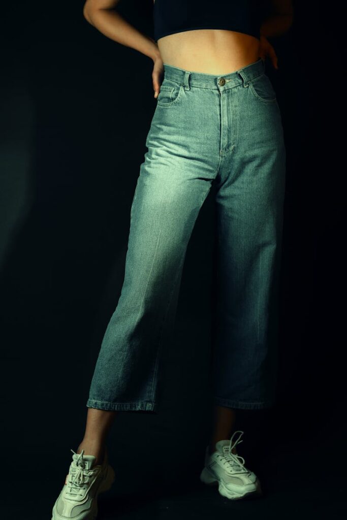 Close-up of a person wearing cropped jeans and sneakers in a stylish pose.