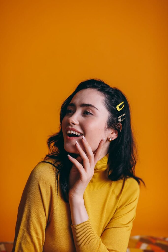 Creative portrait of a happy woman in a yellow outfit with a vivid yellow background.