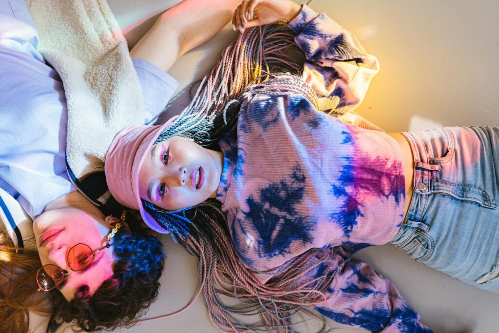 Friends enjoying casual time together in colorful tie-dye fashion. Shot indoors with a playful, vibrant mood.