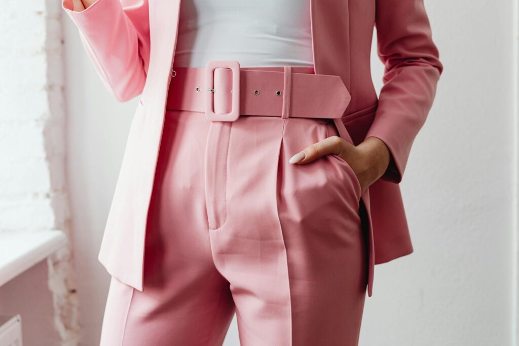 Close-up of a woman in a stylish pink suit, hand in pocket.