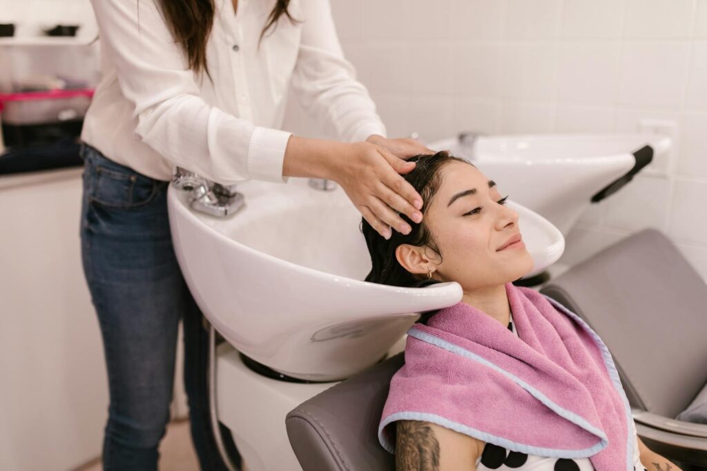 A woman enjoys a relaxing hair wash at a modern salon, symbolizing self-care and pampering.