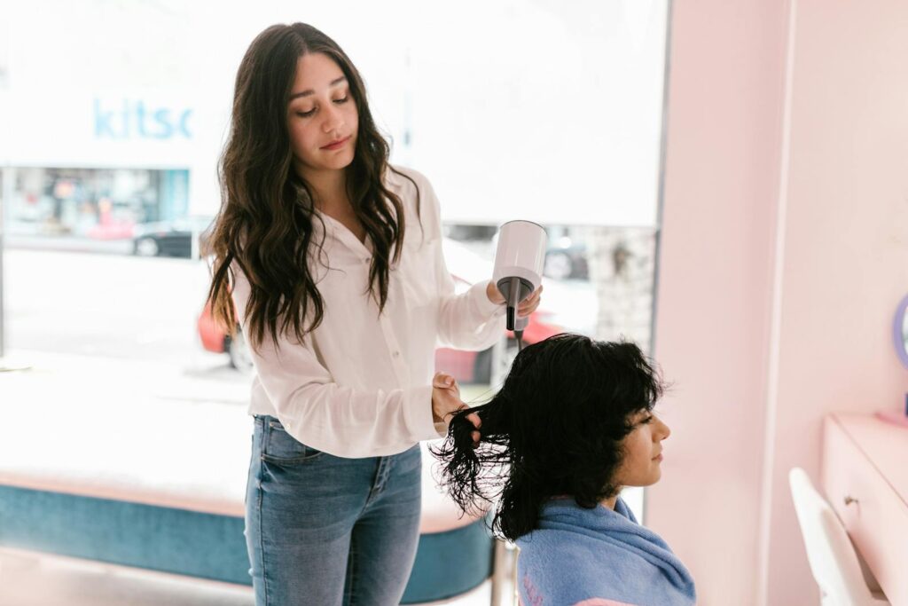 A hairdresser dries a client's hair in a modern salon setting, providing expert hairdressing services.