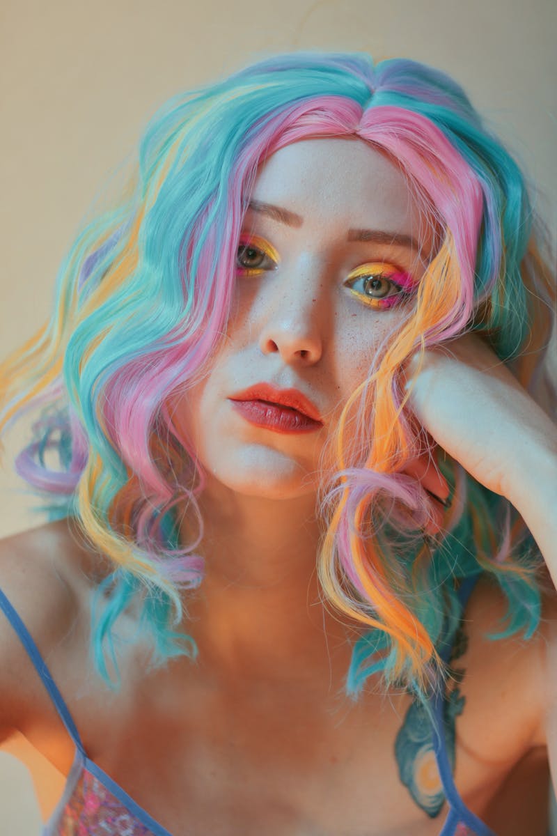 Colorful portrait of a woman with vivid multicolored hair and makeup, expressing creativity and fashion style.