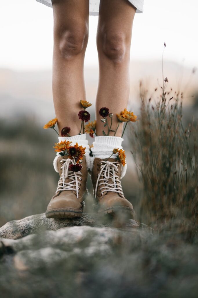 Artistic capture of legs in boots adorned with wildflowers, blending fashion and nature.