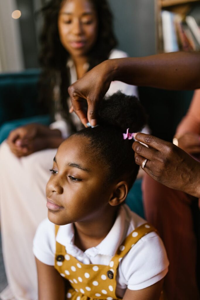 A loving parent styles her child's hair in a cozy and intimate setting.