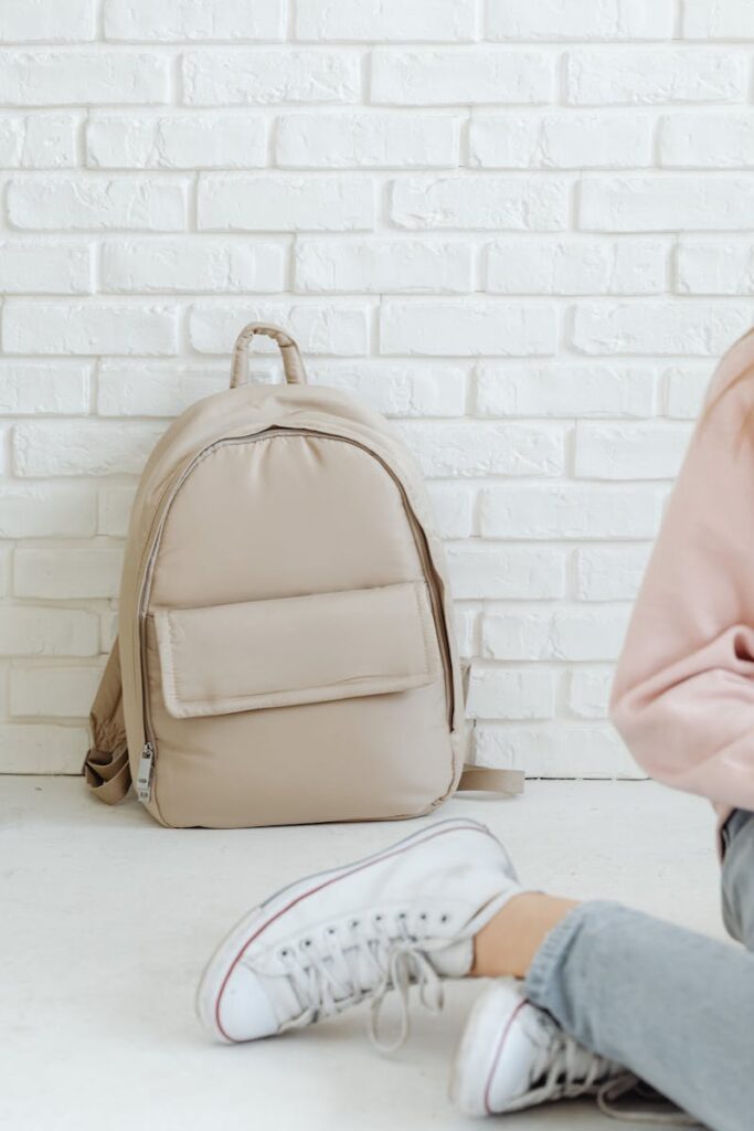 Stylish beige backpack resting against a white brick wall, perfect for lifestyle and travel themes.