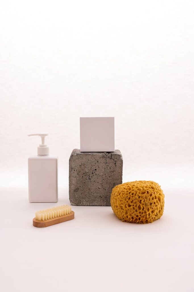 Stylish minimalist display of bathroom essentials including dispenser, sponge, and brush.