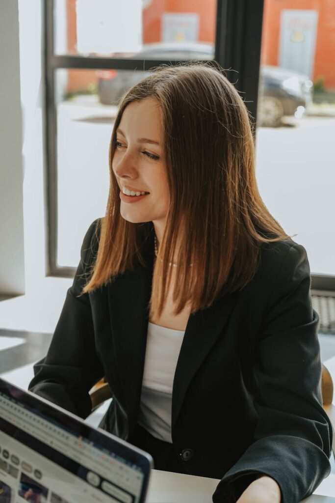 Young woman in formal attire smiling in a bright and modern office environment.