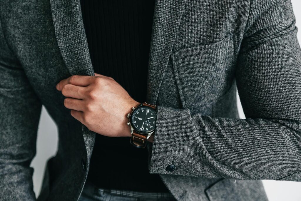 Close-up of a man in a gray suit showcasing a stylish wristwatch. Elegant and professional fashion.