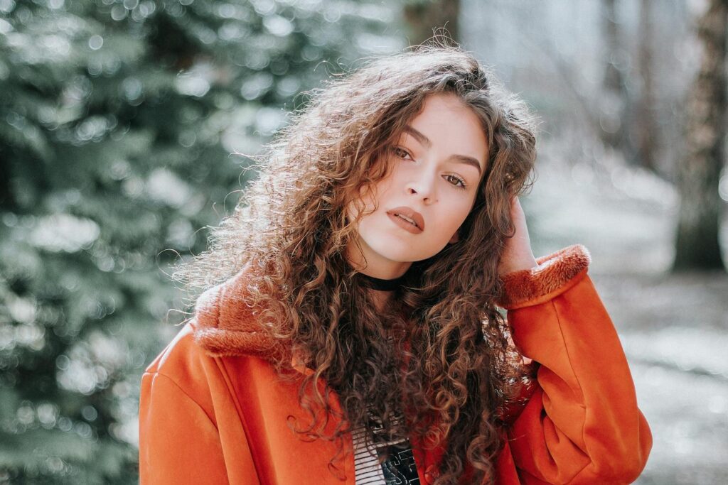 Captivating outdoor portrait of a young woman with curly hair in Vilnius park.