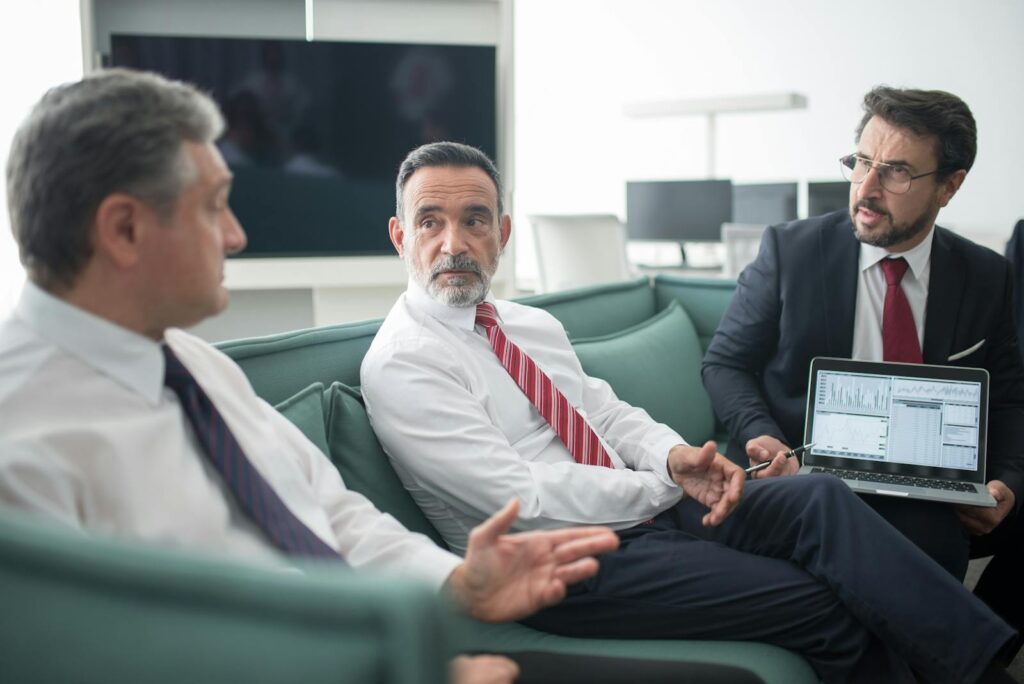 Businessmen discussing corporate strategy during a meeting in modern office setting.